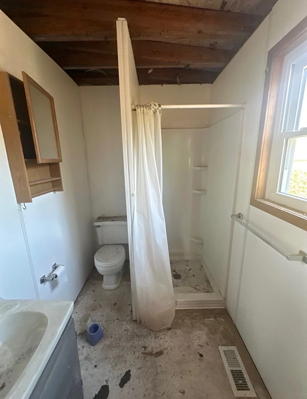 Water-damaged bathroom with an exposed, rotted ceiling before restoration