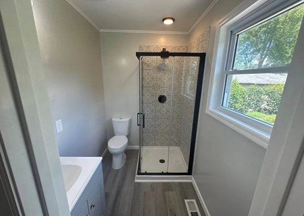 Finished bathroom with a new tiled shower, vanity, and flooring