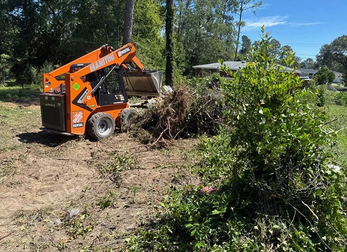 Skid steer clearing storm debris from a property