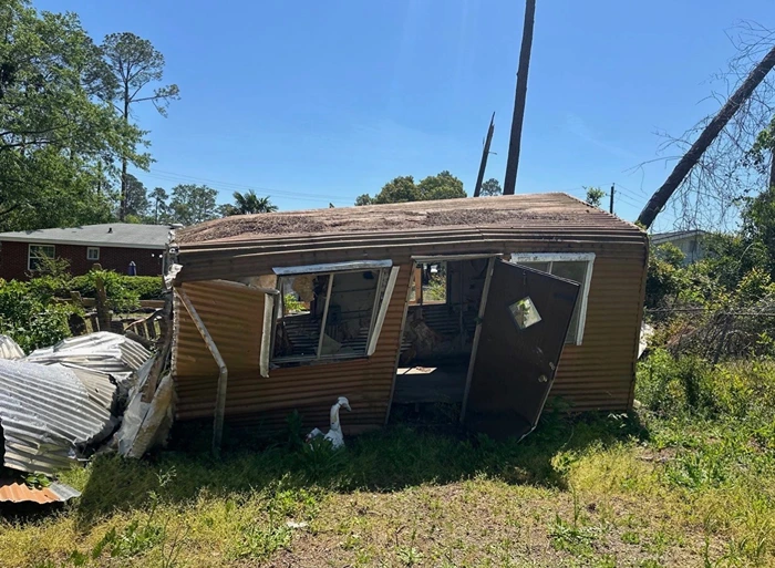 Structure with storm-collapsed siding and roof damage